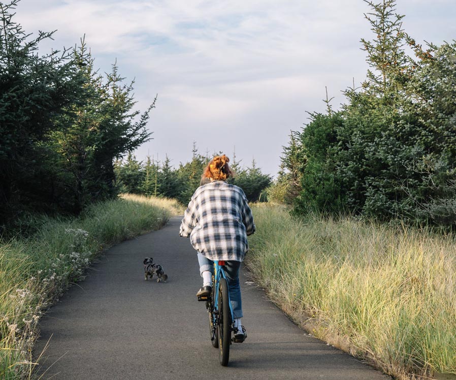 Screenshot woman riding a bicycle in with a dog on a bike path